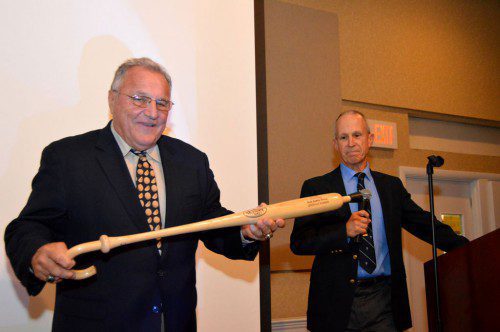 RETIRED BASEBALL COACH Frank Carey tries out one of the joke gifts presented to him at his retirement and roast Saturday night, a cane shaped as a baseball bat. Standing at right is former coach and teacher Peter Hill. (Bob Turosz Photo)