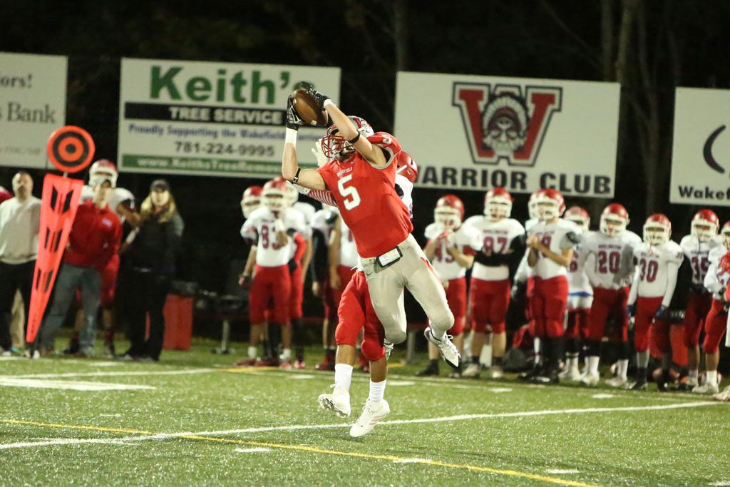 TIGHE BECK, a junior wide receiver (#5), goes up to make a sensational catch which was good for a 20 yard gain. That helped set up Wakefield’s fourth touchdown of the game as the Warriors routed Burlington, 35-14, Friday night at Landrigan Field. (Donna Larsson Photo)