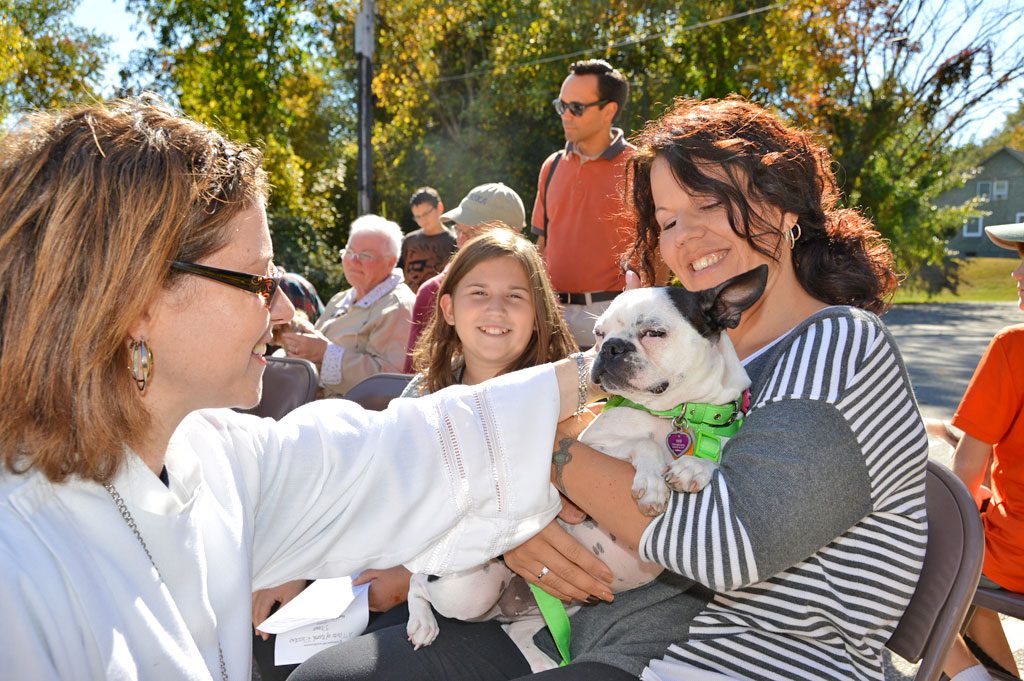 REV. RACHEL FISHER, pastor of the Aldersgate Methodist Church, blesses Letty, a one–year–old Boston Terrier owned by Carolyn Costantino, (right) and her daughter Deanna (center) at Aldersgate's annual Blessing of the Animals on Sunday. (Bob Turosz Photo)