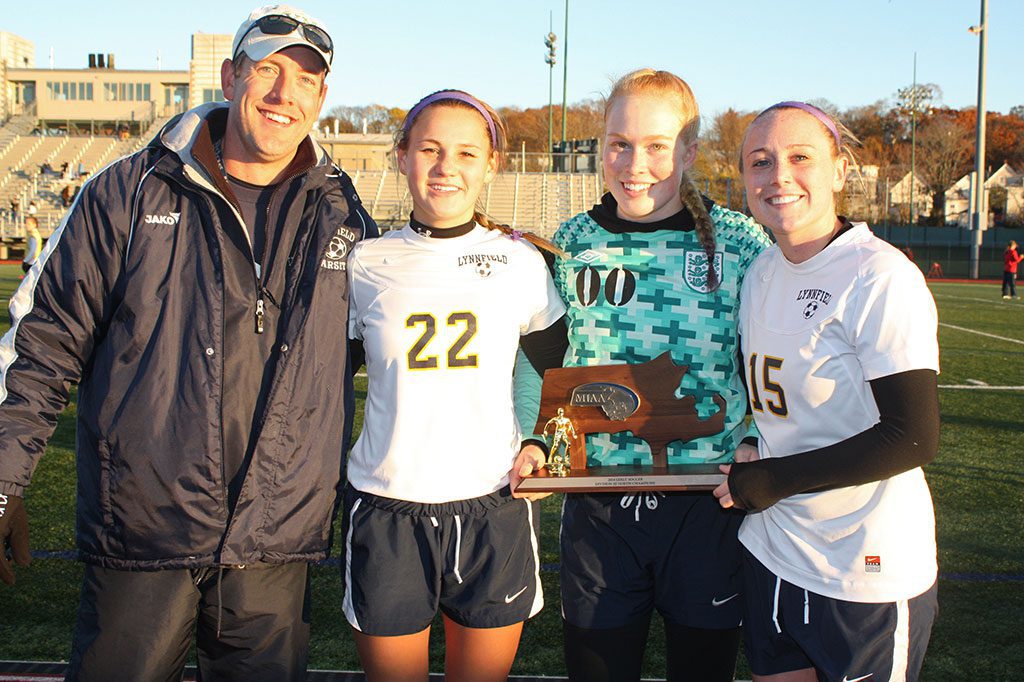 GIRLS’ SOCCER head coach Mark Vermont celebrates winning the Pioneers’ third Division 3 North championship with senior captains, from left, Emily Scollard, Hannah Travers and Paige MacEachern after the Pioneers defeated archrival North Reading 3-1 at Manning Field on Saturday, Nov. 15.  (Dan Tomasello Photo)