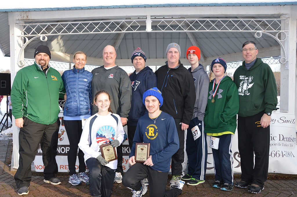 THE WINNERS of the 2014 North Reading 5K Turkey Trot, (Nicole Roberts and Mark Rollfs kneeling above), were the recipients of the annual Fred Keyes award winner given in memory of the late NRHS teacher and avid runner. Standing, from left: Mark Bisognano, president of the North Reading Hall of Fame; Michelle, Mike, Fred, Joe, Doug and Brendan Keyes and Joe Davis, Turkey Trot race director. (Bob Turosz Photo)