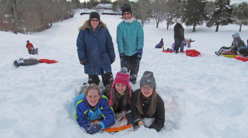 THE Callaghan family and friends took a break from sliding the hill at Bear Hill Golf Course on Wednesday, a no-school day in Wakefield. Shown standing, are Catherine Callaghan, left, and Michelle Mauriello. (Gail Lowe Photo)