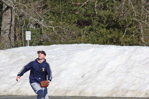 ANDY ROBINS, a junior outfielder and catcher, tracks a fly ball during modified preseason practice held in the high school parking lot against a backdrop of large mound of snow. Snowmaggedon 2015 extended the winter season well into April until this week, when the mercury finally rose into the 60's and 70's. (Maureen Doherty Photo)