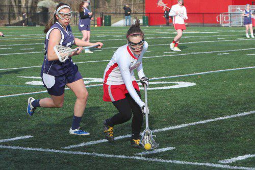 SENIOR CAPTAIN Gianna Tringale (right) goes to scoop up a ground ball during a recent Warrior game. Since that 11-9 triumph over Peabody, the WMHS girls’ lacrosse team has suffered back-to-back losses against Lexington and Reading. (Donna Larsson File Photo)