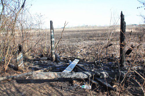 THE FIRE that ultimately consumed 65 acres of the Reedy Meadow marsh on May 6 is believed to have started at the observation tower that stood on four posts about eight feet above the marsh. These portions of the posts are all that remain of the structure. (Maureen Doherty Photo)