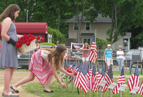 ERIN DONALD (right), a fifth grader at Galvin Middle School, and her cousin Jillian Wallace, a sixth grader from North Reading, place long-stemmed roses at memorial plaques of deceased veterans during the West Side Social Club’s Memorial Day ceremonies at Moulton Park. (Mark Sardella Photo)