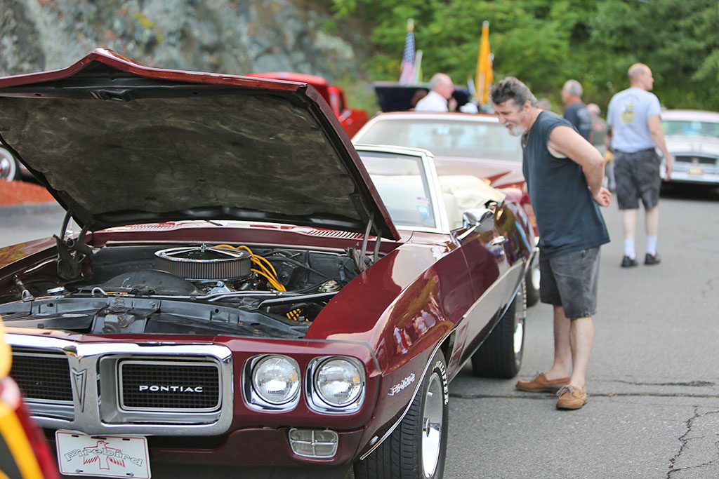 CHUCK GALE checks out this Pontiac Firebird last night during a Classic Car Show at Genesis HealthCare Wakefield Center on Bathol Street in Greenwood. (Donna Larsson Photo)