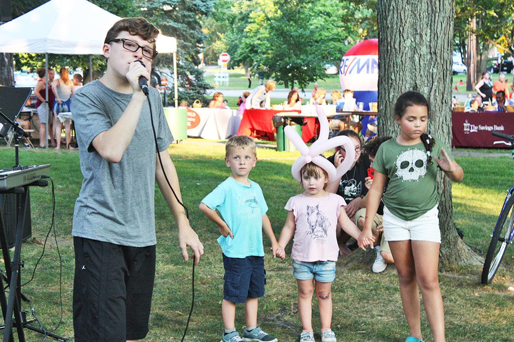 YOUNGSTERS joined hands while singer Angy Paleologos, a rising eighth grader at LMS, performed “Heard it at Sunset” at the Rotary Club’s summer concert series last week. He was inspired to write the song after hearing about the Boston Marathon bombings. He donates the proceeds from downloads of his music video of this song to the One Fund. (Maureen Doherty Photo)