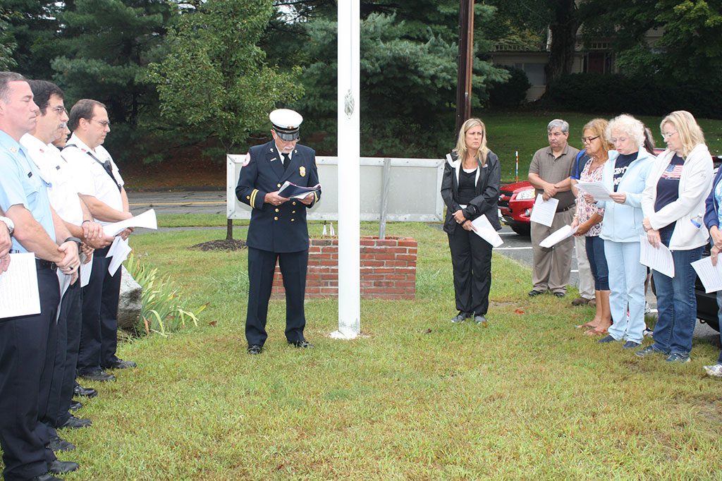A COLD AND DREARY morning did not prevent over two dozen residents and first responders from attending the fire department’s ceremony commemorating the 14th anniversary of the Sept. 11, 2001 terrorist attacks, conducted by (center) Fire Chaplain Rev. Dennis Bailey. (Dan Tomasello Photo)