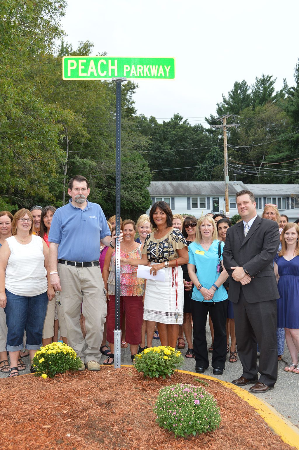 THE LITTLE SCHOOL DRIVEWAY has been renamed Peach Parkway in memory of the late Thea Peach, a longtime employee at the school who passed away earlier this year. On hand for the dedication ceremony were Thea’s husband Don Peach, (standing to left of the sign), Principal Christine Molle, center, front row and Assistant Superintendent Dr. Patrick Daly, front row, far right, surrounded by the rest if the Little School staff.  (Bob Turosz Photo)