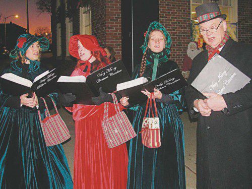 The Dickens Carolers singing holiday tunes in front of The Savings Bank clock at the corner of Main and Chestnut streets during the Holiday Stroll. (Mark Sardella Photo)