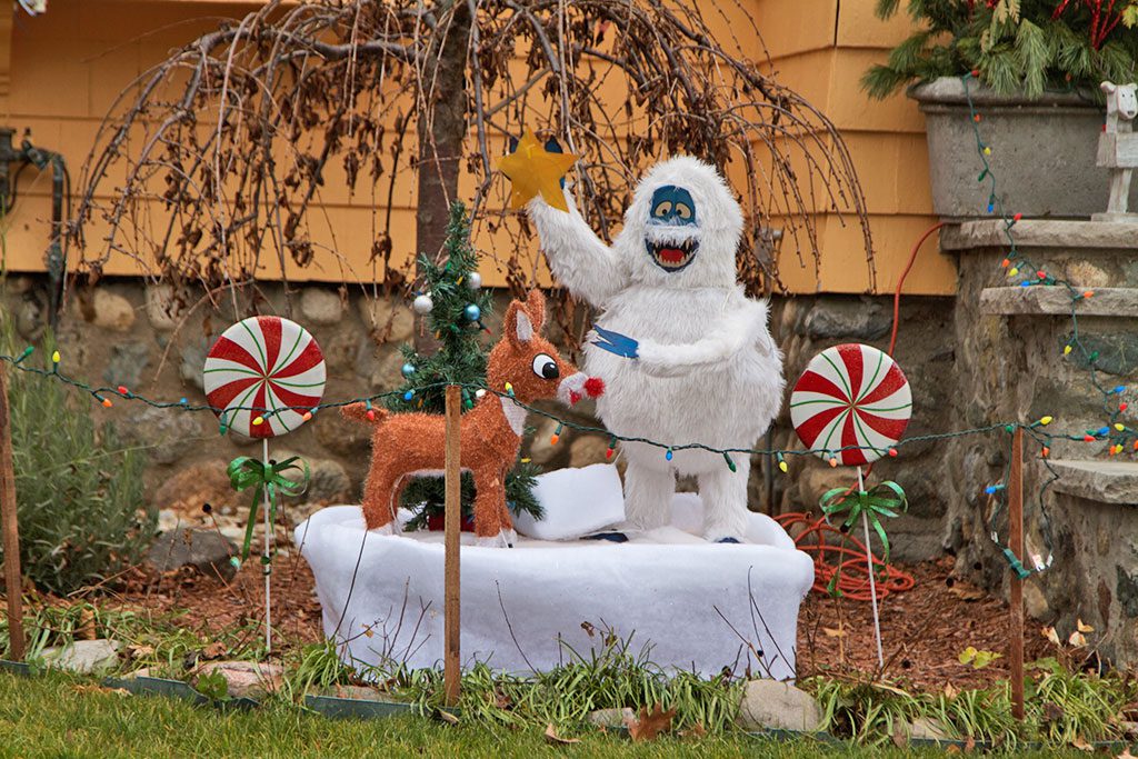 THE ABOMINABLE SNOWMAN prepares to top the Christmas tree with a star under the watchful eye of Rudolph in a scene from the classic Christmas show, Rudolph the Red Nosed Reindeer. The creative display decorates a yard on Glendale Avenue. (Donna Larsson Photo)