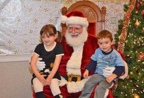 SANTA CLAUS made a couple of new friends at the Reading Co–operative Bank on Sunday: Miajoy and Jimmie Morris, here for the Holiday Lighting Festival. (Bob Turosz Photo)