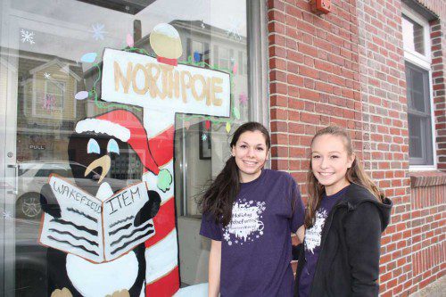 A FESTIVE penguin visiting the North Pole catches up on the latest news back home about the Holiday Stroll in the Wakefield Daily Item. The scene was created from the imaginations of WMHS art students Amber Drinkwater (left), Brianna Racamato and (missing from photo) Helen Salvatore. Dozens of WMHS art students helped transform downtown Wakefield storefronts into a colorful winter wonderland to celebrate the holidays in conjunction with the Holiday Stroll events. (Maureen Doherty Photo)