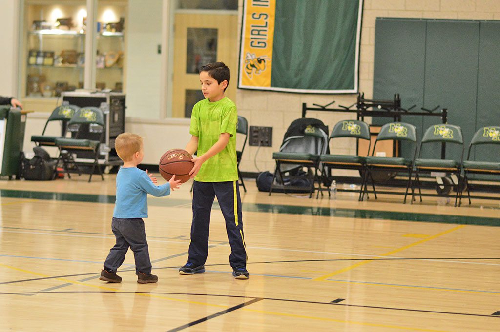 CHARLIE ROSA (right) shares the ball with Sebastian Putnam as kids took to the court during half time of Friday night's girls' varsity basketball game. Both boys are the sons of NRHS teachers. (Bob Turosz Photo)