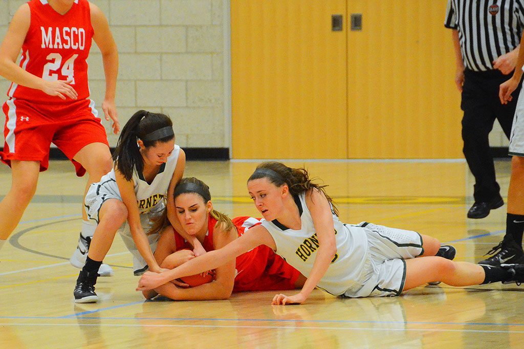 SENIOR CAPTAINS Carly Swartz (left) and Julia McDonald (right) go to the floor to fight their Masco opponent for the loose ball. (John Friberg Photo)