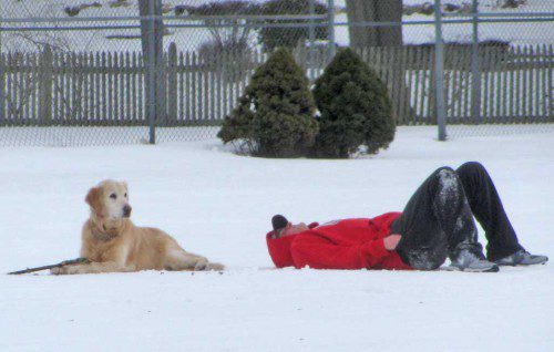 A DOG and his master take a break from playing in the snow on Veterans Field yesterday. (Mark Sardella Photo)
