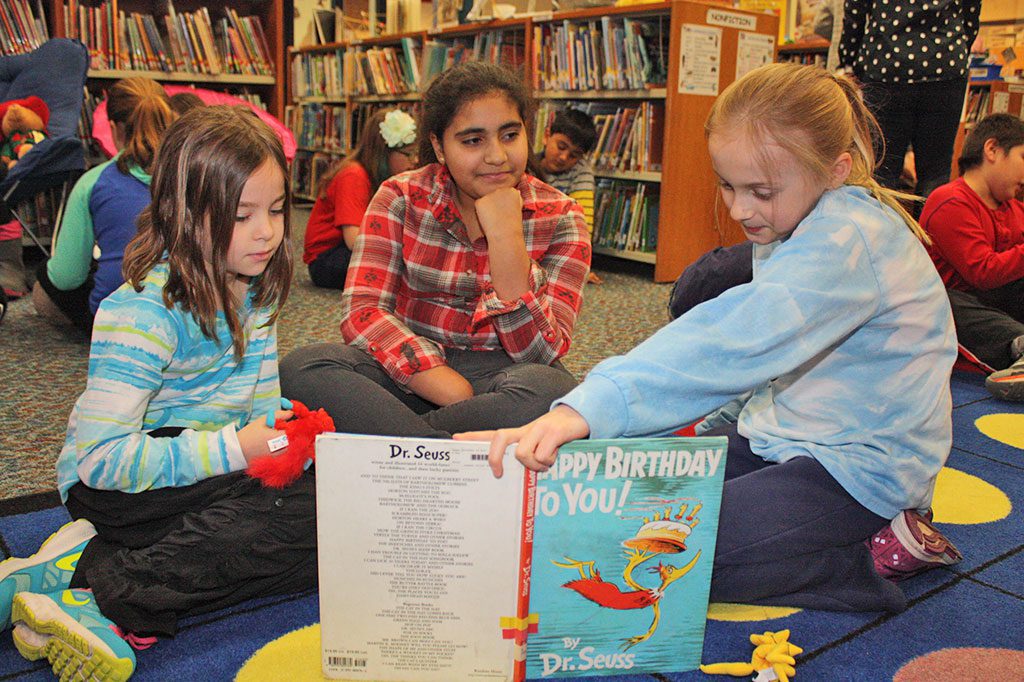 TO CELEBRATE National Reading Month, which officially kicked off at the Summer Street School on the 112th birthday of Dr. Seuss March 2, fourth-grader Olivia Goguen (far right) takes a turn reading aloud from one of his books, “Happy Birthday to You!” to her reading buddies, second-grader Hayden Service (left) and fourth-grader Hazel Gonzalez (center). (Maureen Doherty Photo)
