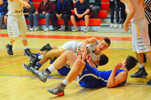 TENACIOUS. Senior Justin Dorosh goes to the floor between two Bedford players to fight for the loose ball. (John Friberg Photo)