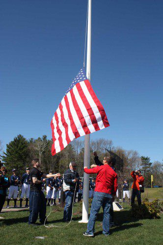 OLD GLORY billows in the breeze as Johnny “O’D” O’Donnell’s brothers and father raise a new flag on the new lighted flagpole erected in his memory at the LHS baseball field last Saturday. (Maureen Doherty Photo) 